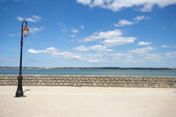 Lantern on a beach with a low stone wall and sea in the background