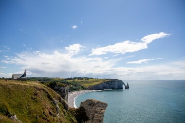 Obraz premium Beautiful seascape with green-covered cliffs and a sandy coastline in Etretat, France