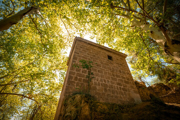 Slender tower of the Templars in the Fuentes del Marques area in Caravaca de la Cruz, Murcia, Spain among leafy trees