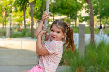 cute girl swinging on a rope at the playground