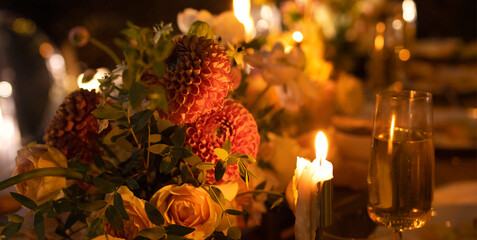 Wedding table for guests, decorated with candles, are served with cutlery and crockery and covered with yellow tablecloth