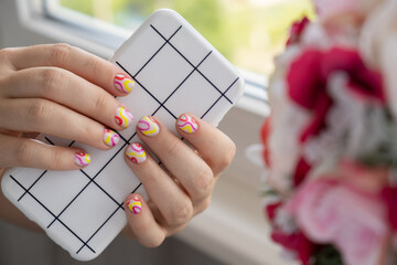 Stylish summer colorful nails female manicured hands holding mobile phone. Closeup of manicured nails of woman hand. Summer style of nail design concept. Beauty