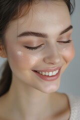 Obraz premium A close-up shot of a woman smiling with her eyes closed. Perfect for advertising and beauty campaigns