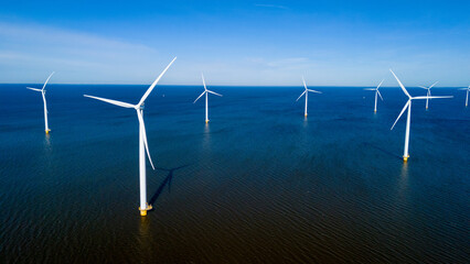 A group of wind turbines elegantly spin in the ocean off the coast of the Netherlands in Flevoland...
