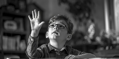 A young boy wearing glasses is raising his hand. Suitable for educational concepts