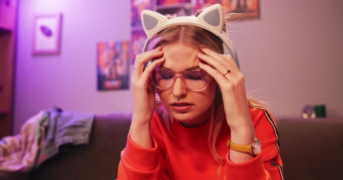 Gamer, frustration and headache with challenge, esports and stress or mistake. Woman, rage and technology with neon, lounge and apartment or home living room with console and glasses for play