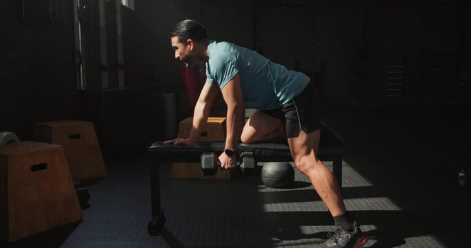 Dumbbell row, exercise and man in gym for muscle, wellness and sports for body health. Power, weightlifting and strong bodybuilder training for fitness, serious and workout for energy with equipment