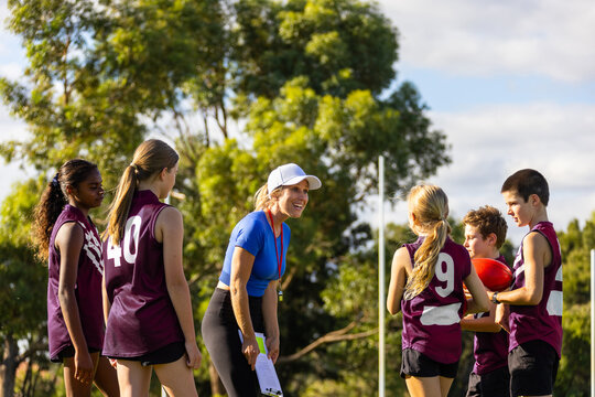 enthusiastic female coach encouraging her young football team