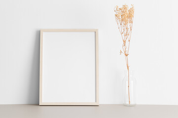 Wooden frame mockup with a gypsophila decoration on the beige table.