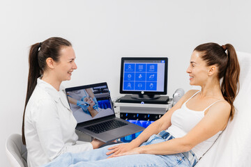 A female cosmetologist in a modern beauty salon holds a laptop with a broadcast of the hydrolifting procedure for facial cleansing. Cosmetic services advertising concept.