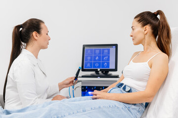 A female cosmetologist-dermatologist talks to a client sitting in a comfortable salon chair....
