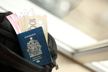 Naklejka premium Canadian passport and dollar money bills with airline tickets on backpack close up