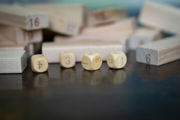 Four wooden dices foreground and many wooden blocks background with numbers. 
