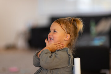 little girl with hands under chin smiling and looking out of frame