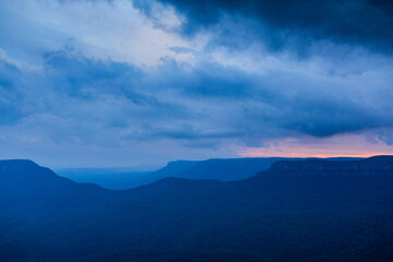 Dramatic stormy sky over layered blue mountains at nightfall