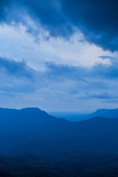 Dramatic stormy sky over layered blue mountains at nightfall