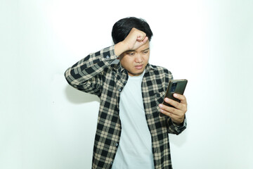 Young Asian man holding his mobile phone with sad expression