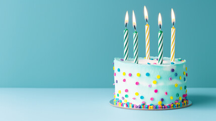 A playful and bright birthday cake with polka dots and five lit candles on a blue backdrop