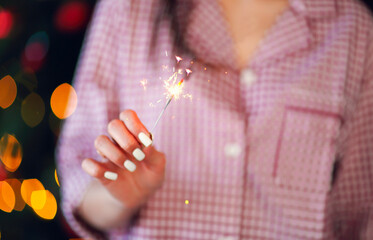 Happy woman with sparkler and champagne against Christmas tree