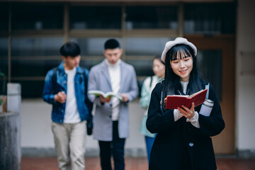 An Asian female student walks through the campus, earnestly flipping through her notes, embodying the campus atmosphere.