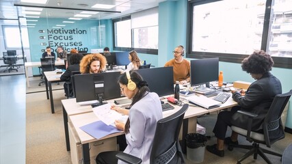 Busy businesspeople working at computer desks in creative office