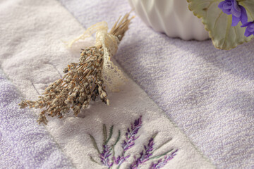 Lilac embroidered towel and dry lavender flowers.  Serenity, stress-relief concept.