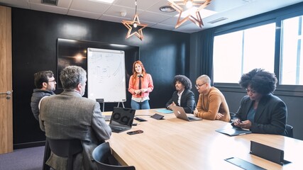 Businesswoman giving presentation to diverse colleagues in conference room