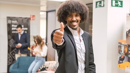 Happy confident creative businessman showing thumbs up in office