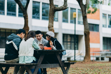 Asian university students are dining on campus while discussing coursework. They have chosen to use reusable, eco-friendly tableware, embodying the concept of sustainable living.