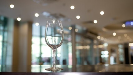Empty glass on the bar counter. Transparent empty wine glass standing on a bar counter on a blurred...