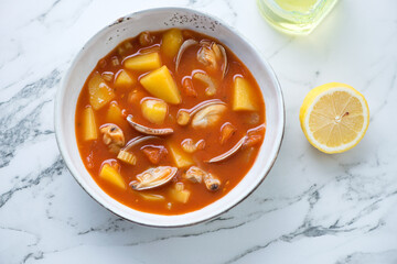 Bowl of manhattan chowder with vongole clams on a white marble background, horizontal shot, top view