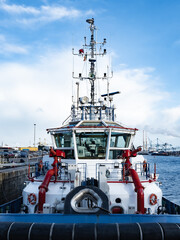 A front view of tugboat with white superstructure and red fire-fighting canons.
