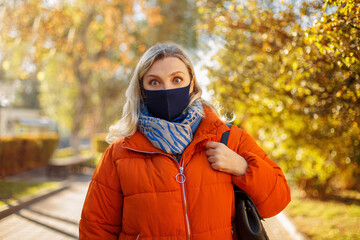 Female in mask walking in autumn park