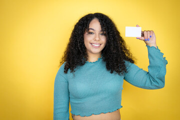African american woman wearing casual sweater over yellow background smiling and holding white card