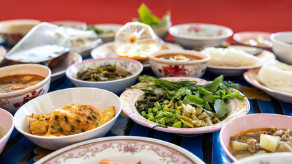 A close-up view of khanom jeen, curry, fried eggs, stir-fries and many other dishes packed in bowls.