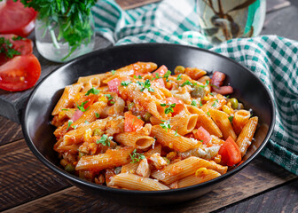 Classic italian pasta penne arrabbiata with vegetables on wooden table. Penne pasta with sauce arrabbiata. Top view, overhead