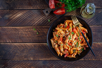 Classic italian pasta penne arrabbiata with vegetables on wooden table. Penne pasta with sauce arrabbiata. Top view, overhead - obrazy, fototapety, plakaty