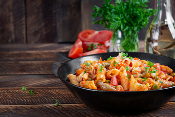 Classic italian pasta penne arrabbiata with vegetables on wooden table. Penne pasta with sauce arrabbiata. Top view, overhead - 784439440