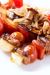 Grilled shashliks with vegetables, chanterelle mushrooms and pork. Close up.	