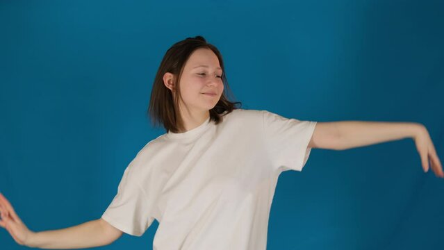 Lady moves head from side to side on blue background. Pleased woman performs dance movements embodying grace and agility