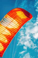 Obraz premium A person flying a large orange kite in the sky. Suitable for outdoor activities promotion
