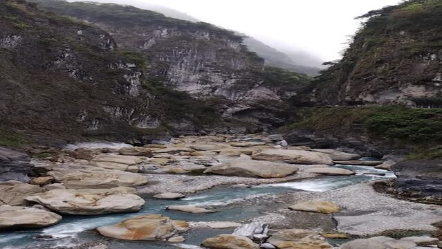 Vertical video of Liwu river in steep gorge, narrow canyon in Taroko Nationalpark, Taiwan. Big rocks laying in water, are washed out. High cliffs, mountains partial wooded