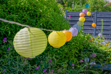 Summerly garden scene with colorful lampions hanging in a row.