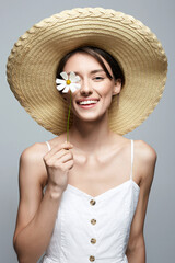 village girl in hat with flower. beautiful smiling young woman with chamomile