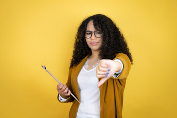 African american business woman with paperwork in hands over yellow background with angry face, negative sign showing dislike with thumb down