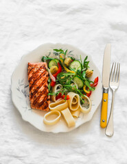Balanced lunch - grilled salmon, pasta and fresh vegetable salad on a light background, top view