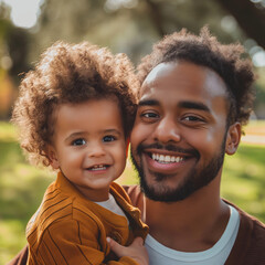 Smiling African American father holding toddler son outdoors, celebrating Father's Day with a joyous embrace. Concept of family, love, and Father's Day.