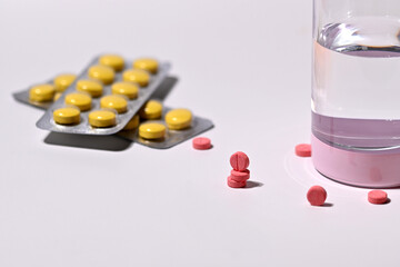 Colorful Pills and a Glass of Water on a White Background