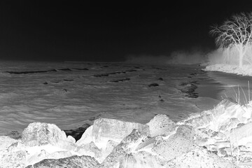 waves breaking on the beach in black and white film negative