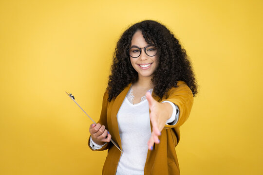 African american business woman with paperwork in hands over yellow background smiling friendly offering handshake as greeting and welcoming